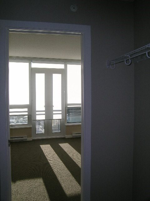 Spacious living room with large windows and a city view, featuring a cozy corner desk and shelving. - 2307 - 833 Seymour Street, Vancouver Downtown