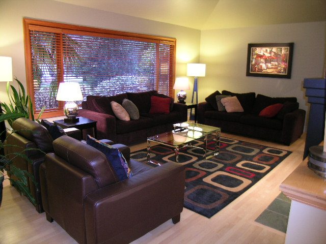 Spacious living room with hardwood floors, a large area rug, and a cozy brown leather sofa set. - 3272 Brookridge Drive, North Vancouver