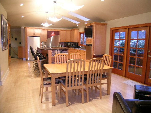 Open-concept kitchen and dining area with hardwood floors, wooden cabinetry, and a view of the living room. - 3272 Brookridge Drive, North Vancouver