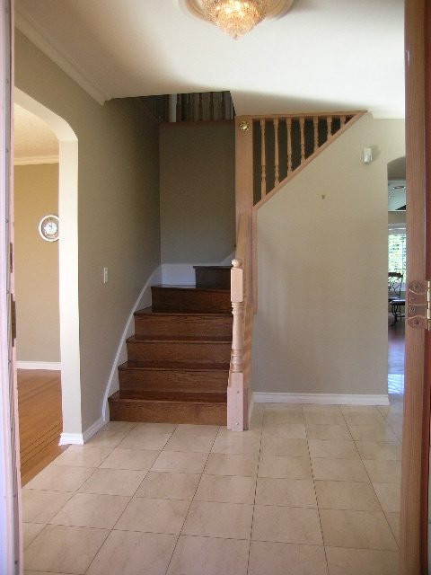 Staircase leading to upper level with wooden banister and tiled floor. - 1875 26th Street, West Vancouver