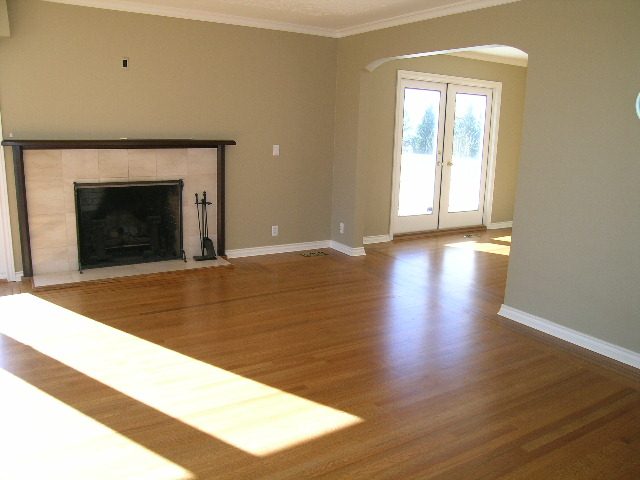 Spacious living room with hardwood floors, a fireplace, and French doors leading outside. - 1875 26th Street, West Vancouver