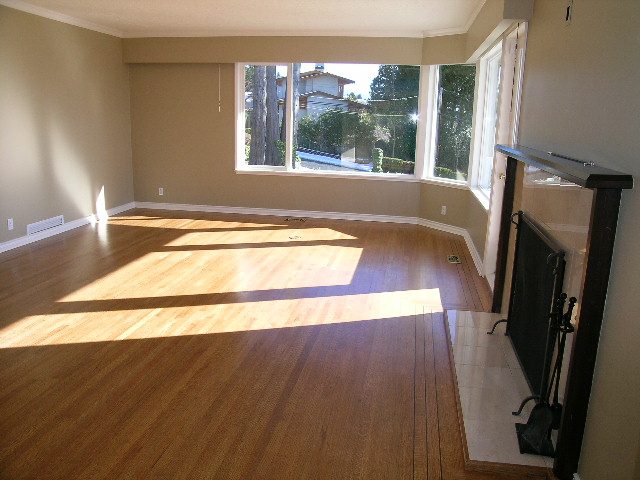 Spacious living room with hardwood floors and a bay window, offering a serene city view. - 1875 26th Street, West Vancouver