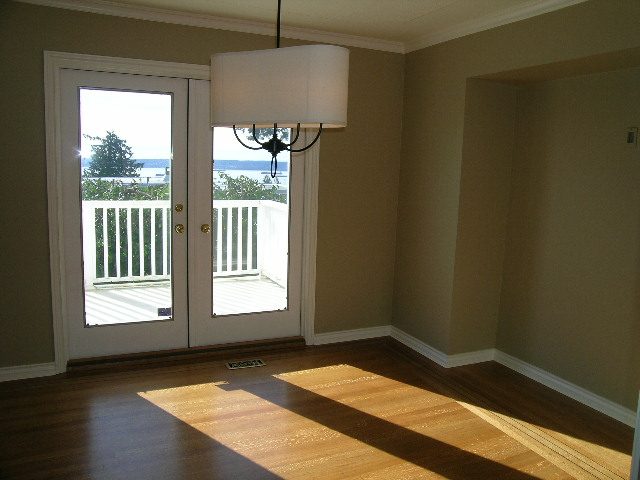 Spacious living room with hardwood floors, French doors leading to a balcony, and a modern chandelier. - 1875 26th Street, West Vancouver
