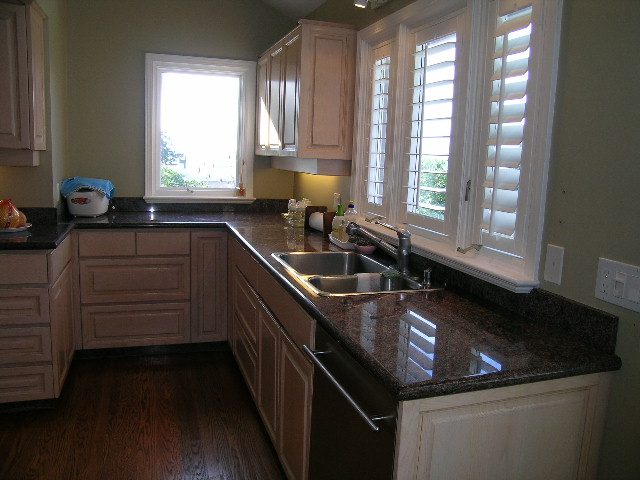 Bright kitchen with granite countertops, hardwood floors, and a window with white shutters. - 1875 26th Street, West Vancouver