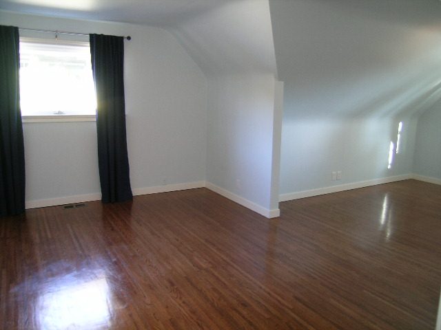 Spacious attic bedroom with hardwood floors and natural light from a window. - 1875 26th Street, West Vancouver
