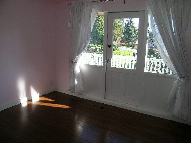 Bright living room with hardwood floors and a view of the garden through the French door. - 1875 26th Street, West Vancouver