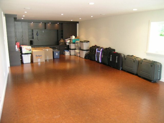 Spacious living room with hardwood floors, storage shelves, and neatly arranged luggage. - 1875 26th Street, West Vancouver