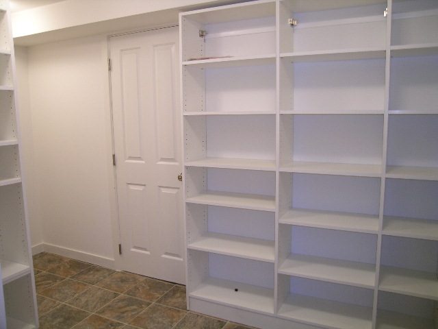 Spacious living room with built-in white shelving and tiled floor. - 1875 26th Street, West Vancouver