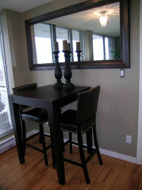 Dining area with black table, chairs, and large mirror reflecting window blinds and chandelier. - 2109 - 1295 Richards Street, Vancouver Downtown