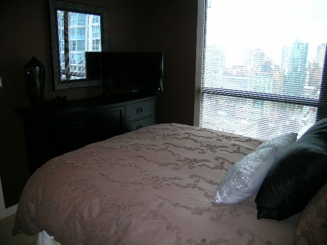 Spacious bedroom with a city view and a cozy bed setup, featuring a flat-screen TV and a dresser. - 2109 - 1295 Richards Street, Vancouver Downtown