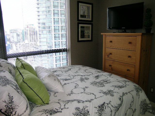 Spacious bedroom with city view, wooden dresser, and toile-patterned bedding. - 2109 - 1295 Richards Street, Vancouver Downtown