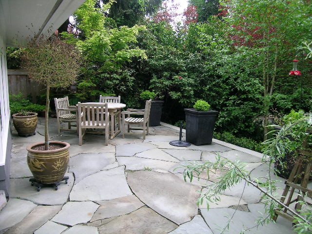 Spacious patio with stone paving, wooden furniture, and lush greenery. - 2795 Palmerston Avenue, West Vancouver