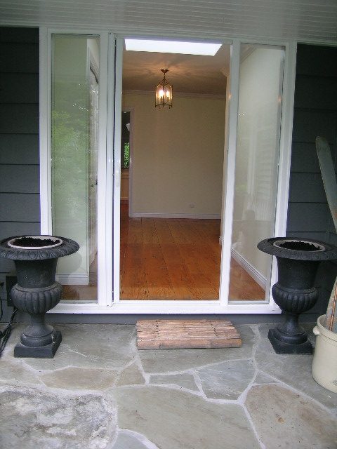 Bright entryway with hardwood floors and a cozy indoor-outdoor feel, featuring a sliding glass door and decorative urns.