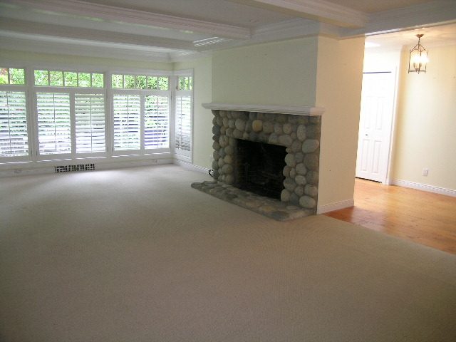 Spacious living room with stone fireplace, hardwood floors, and large windows. - 2795 Palmerston Avenue, West Vancouver