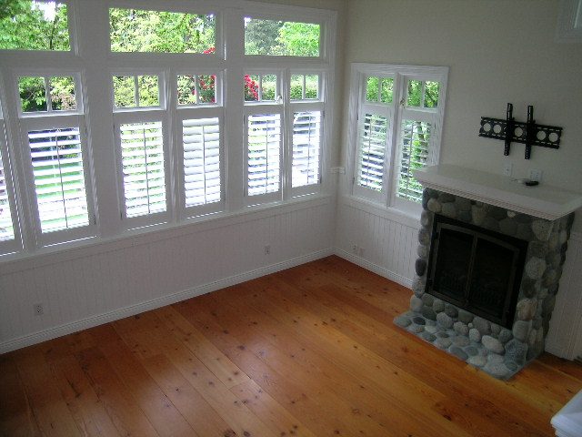 Spacious living room with hardwood floors, large bay windows, and a stone fireplace. - 2795 Palmerston Avenue, West Vancouver