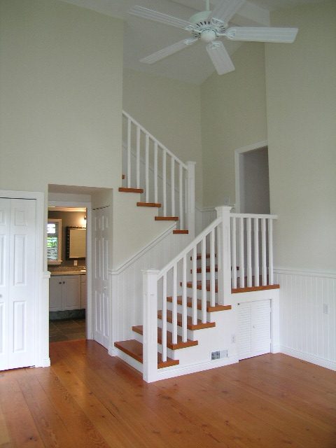 Staircase leading to upper level with hardwood floors and white railings, showcasing a clean and bright interior.