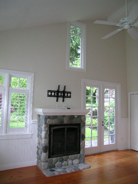 Spacious living room with stone fireplace, hardwood floors, and French doors leading to a garden. - 2795 Palmerston Avenue, West Vancouver
