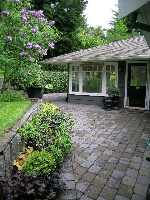 Patio with stone paving and lush greenery, leading to a cozy 4-bedroom house. - 2795 Palmerston Avenue, West Vancouver