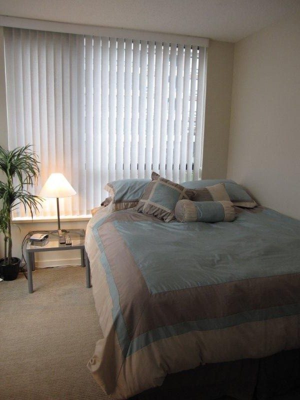 Bright bedroom with a neatly made bed, soft lighting, and a potted plant. - 302-977 Mainland Street, Vancouver Downtown