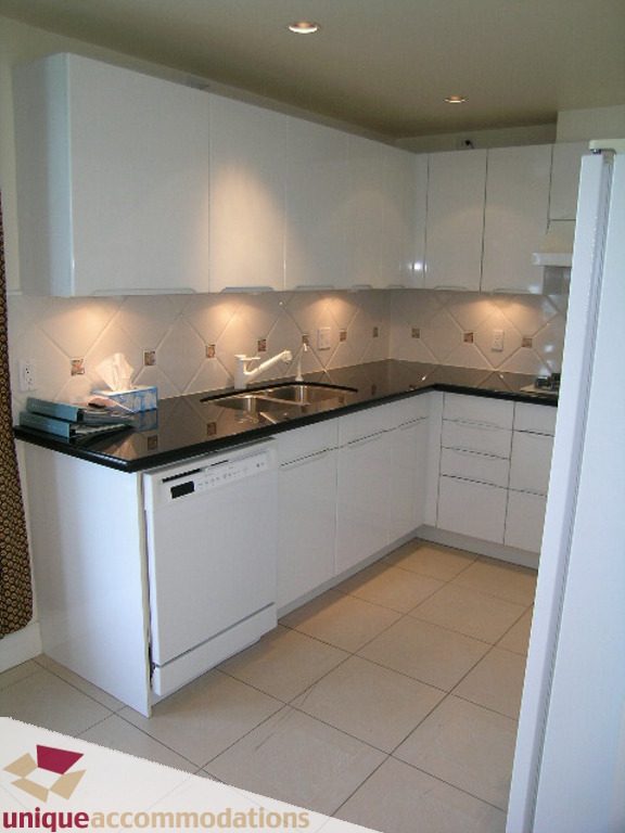 Bright kitchen with white cabinets, black countertops, and tiled backsplash, perfect for a cozy downtown condo.