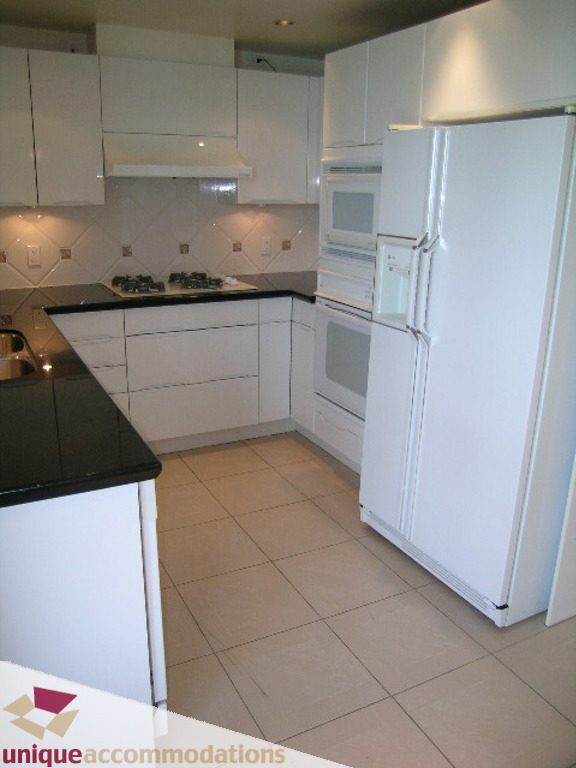 Bright kitchen with white cabinetry, black countertops, and tiled backsplash. - 1903 - 535 Nicola Street, Vancouver Downtown