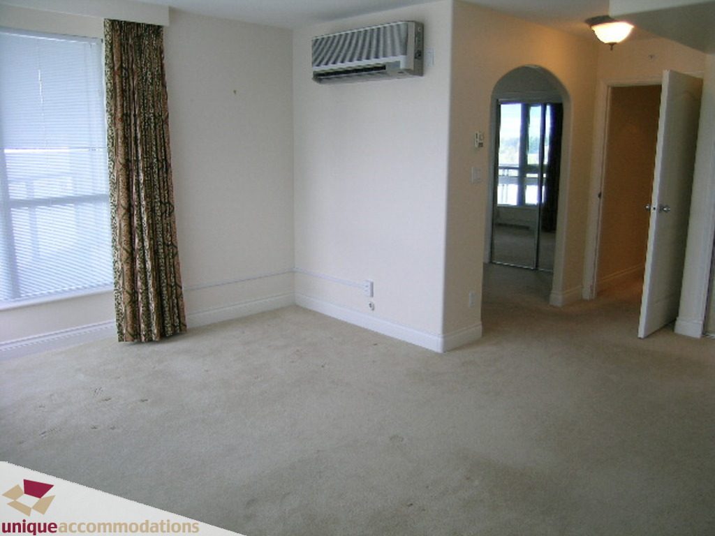 Spacious living room with carpet, arched doorway, and wall-mounted air conditioner. - 1903 - 535 Nicola Street, Vancouver Downtown