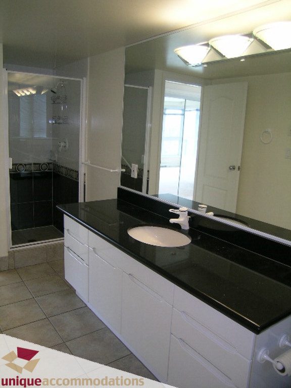 Spacious bathroom with black countertops and a large mirror, showcasing a modern design. - 1903 - 535 Nicola Street, Vancouver Downtown