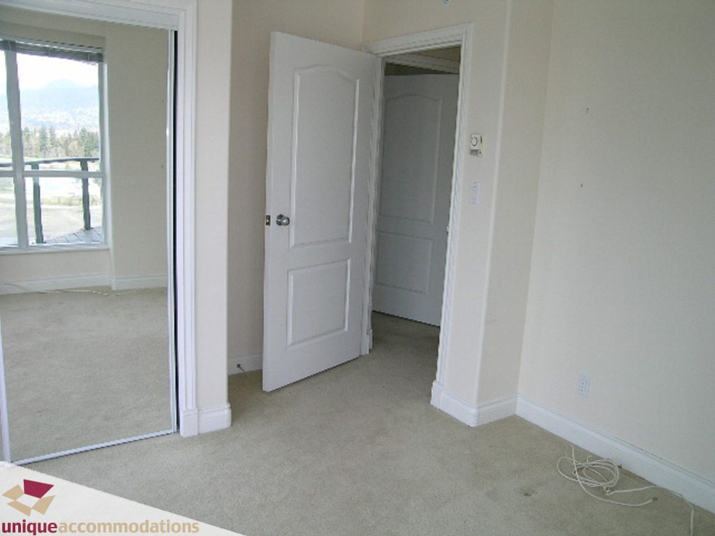 Spacious bedroom with carpeted floor, white walls, and a view of the city through the window. - 1903 - 535 Nicola Street, Vancouver Downtown