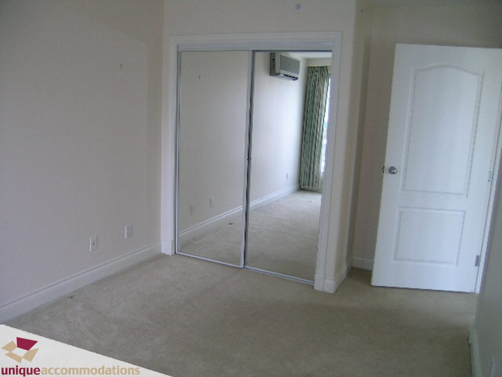 Spacious bedroom with mirrored closet doors and beige carpeting. - 1903 - 535 Nicola Street, Vancouver Downtown