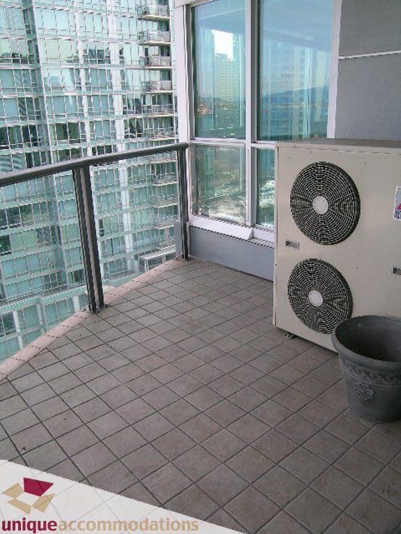 Spacious balcony with tiled flooring and city view, featuring a large air conditioning unit. - 1903 - 535 Nicola Street, Vancouver Downtown
