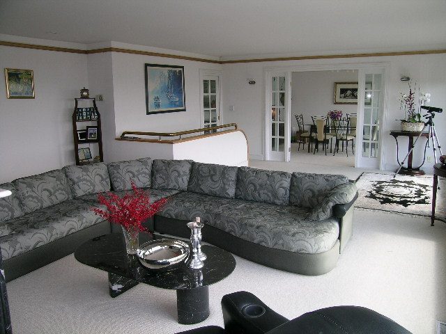 Spacious living room with large sectional sofa, modern coffee table, and glass doors leading to dining area. - 1104 Hillside Road, West Vancouver