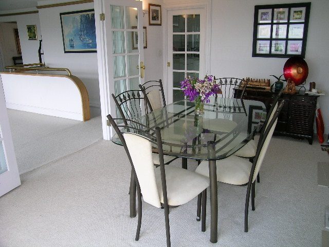 Furnished dining area with glass table, white chairs, and purple flowers. - 1104 Hillside Road, West Vancouver