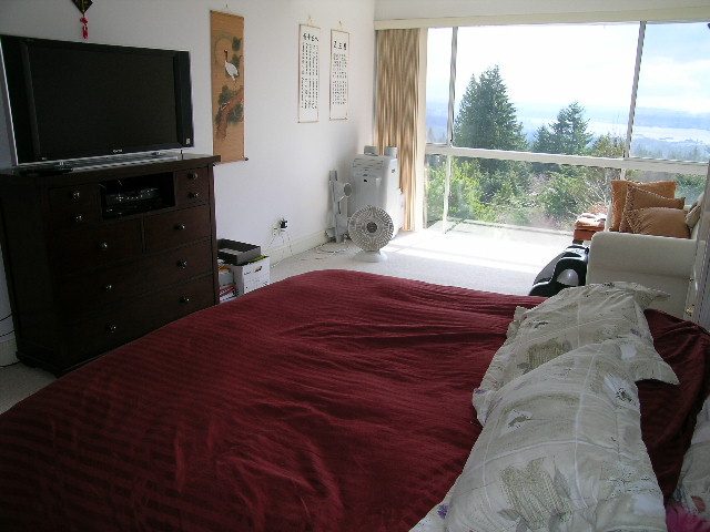 Bright bedroom with maroon bedding and a balcony view of trees. - 1104 Hillside Road, West Vancouver