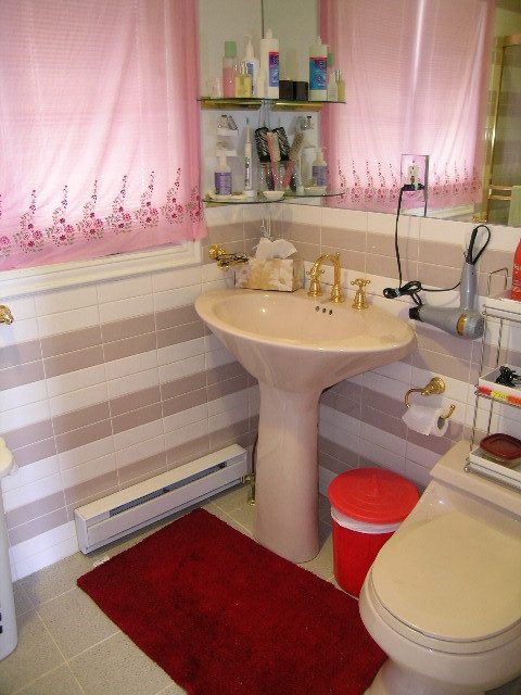 Bathroom with pink floral curtains, striped tile walls, and a red bath mat. - 1104 Hillside Road, West Vancouver