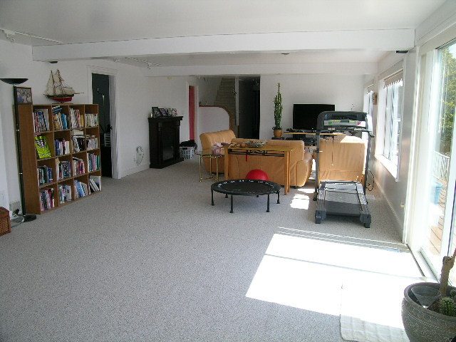Bright living room with bookshelves, modern furniture, and large windows. - 1104 Hillside Road, West Vancouver