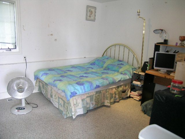 Bright bedroom with twin beds, colorful bedding, and a standing fan. - 1104 Hillside Road, West Vancouver