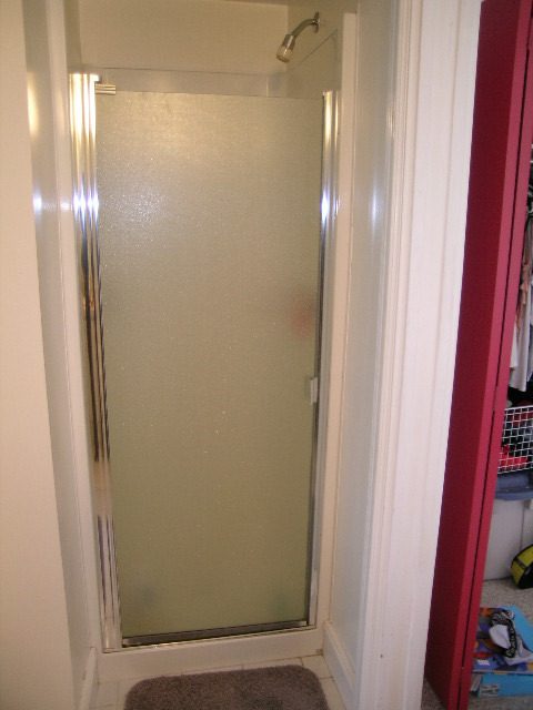 Frosted glass shower door with chrome frame, adjacent to a red wall. - 1104 Hillside Road, West Vancouver