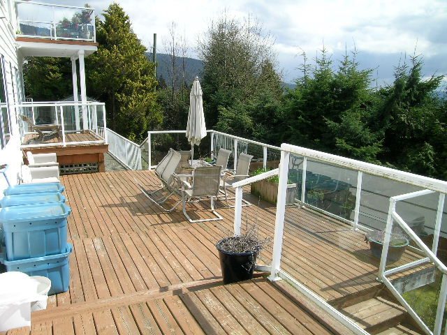 Furnished deck with wooden flooring, outdoor furniture, and a view of trees and mountains. - 1104 Hillside Road, West Vancouver