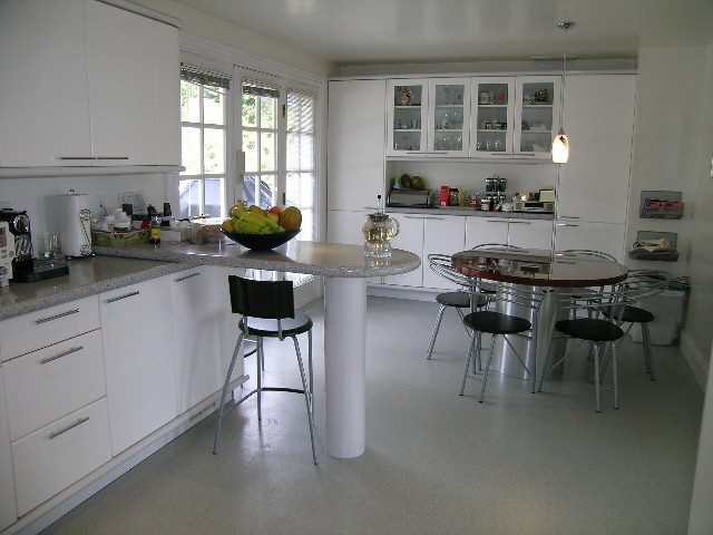 Bright kitchen with white cabinetry, granite countertops, and a modern dining area. - 1104 Hillside Road, West Vancouver