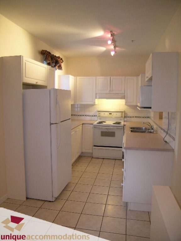 Bright kitchen with white cabinetry, tiled floor, and stainless steel sink. - 1339 West 7th Avenue, Vancouver West Side