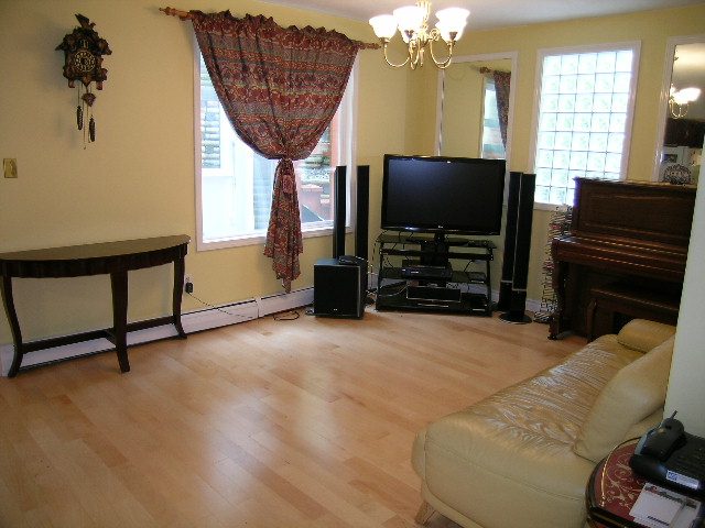 Living room with hardwood floors, a piano, and a flat-screen TV. - 983 Canyon Boulevard, North Vancouver