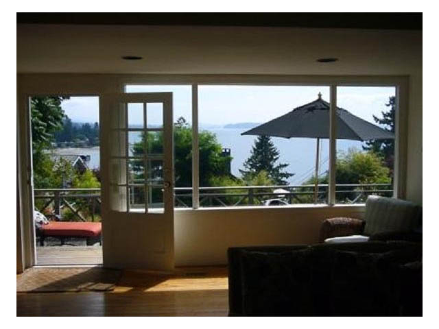Bright living room with hardwood floors and a stunning city view. - 4750 The Highway, West Vancouver