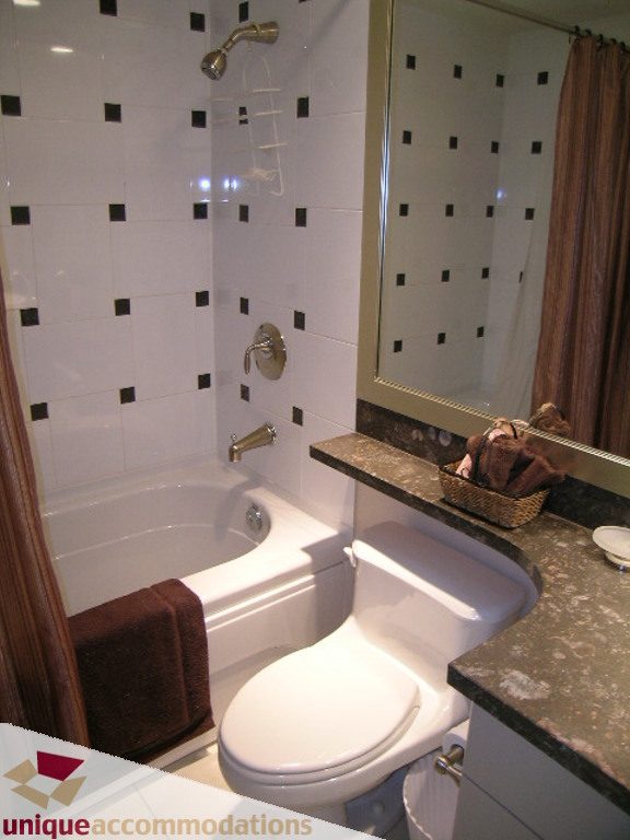 Bathroom with black and white tiled walls, granite countertop, and a bathtub with a shower. - 1401 - 1680 Bayshore Drive, Vancouver Downtown