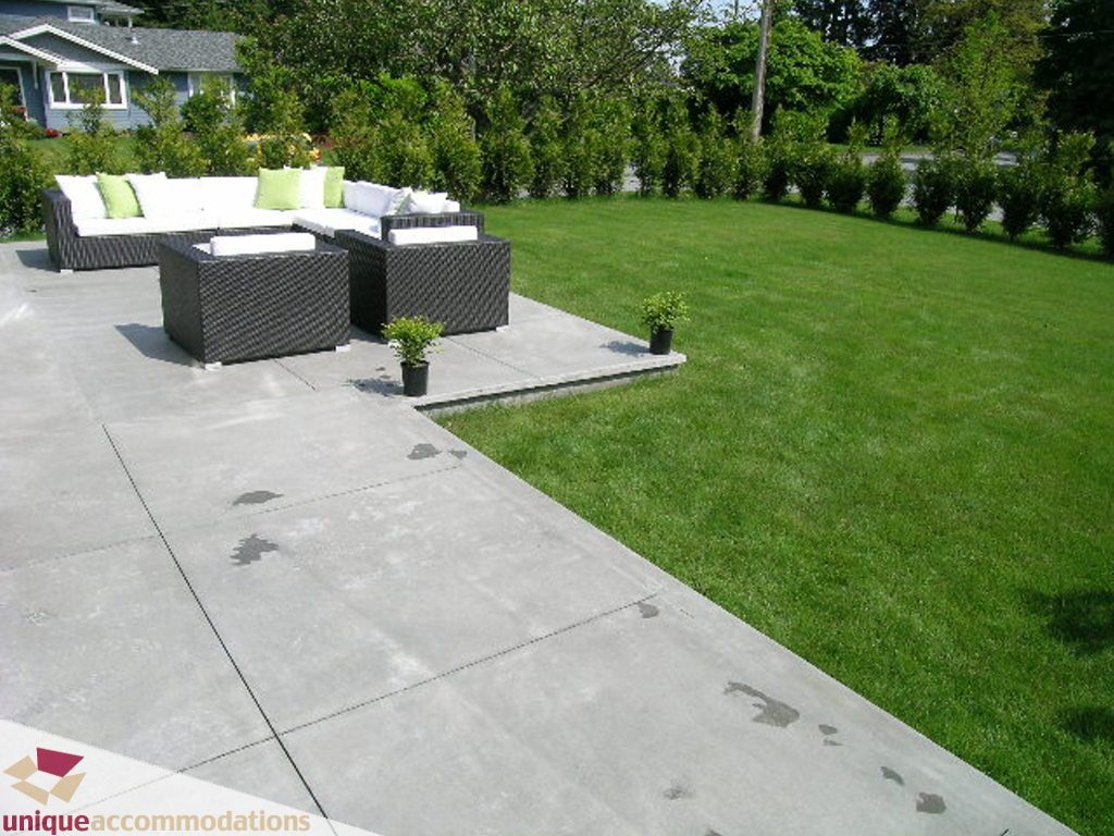 Furnished patio with modern furniture and lush green lawn, perfect for relaxation. - 2015 Lloyd Avenue, North Vancouver
