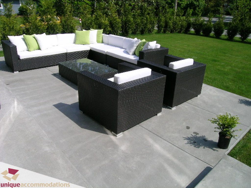 Furnished patio with modern wicker furniture, green and white cushions, and a small potted plant. - 2015 Lloyd Avenue, North Vancouver