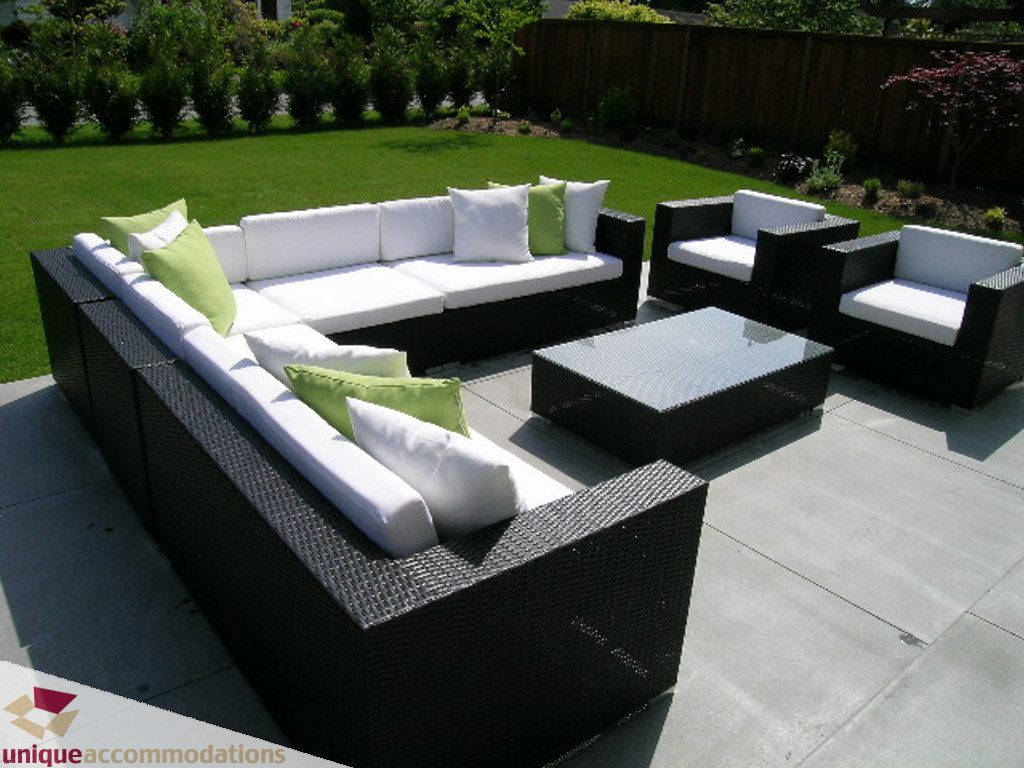Outdoor lounge area with modern wicker furniture, white cushions, and green accents. - 2015 Lloyd Avenue, North Vancouver