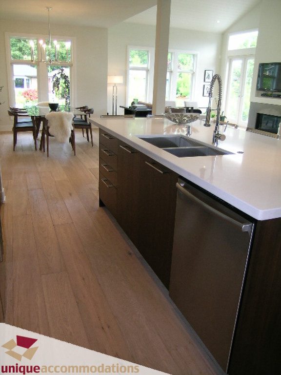 Bright kitchen with white countertops, dark wood cabinets, and hardwood floors, showcasing a modern design. - 2015 Lloyd Avenue, North Vancouver