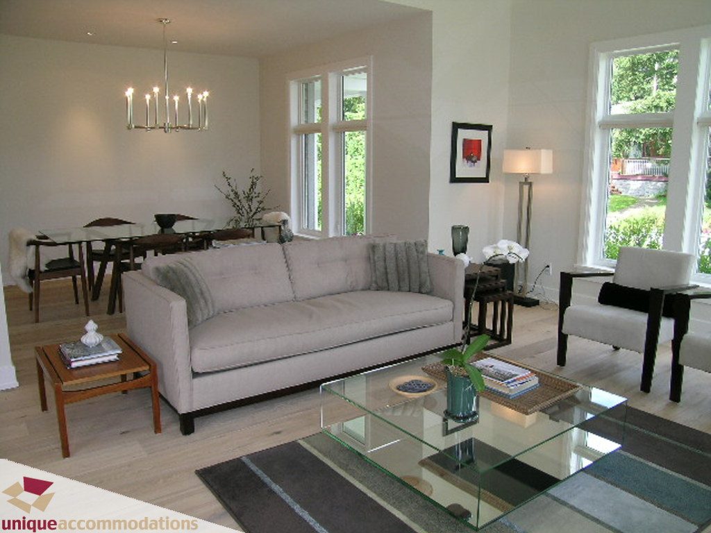 Spacious living room with modern furnishings, large windows, and a glass coffee table. - 2015 Lloyd Avenue, North Vancouver
