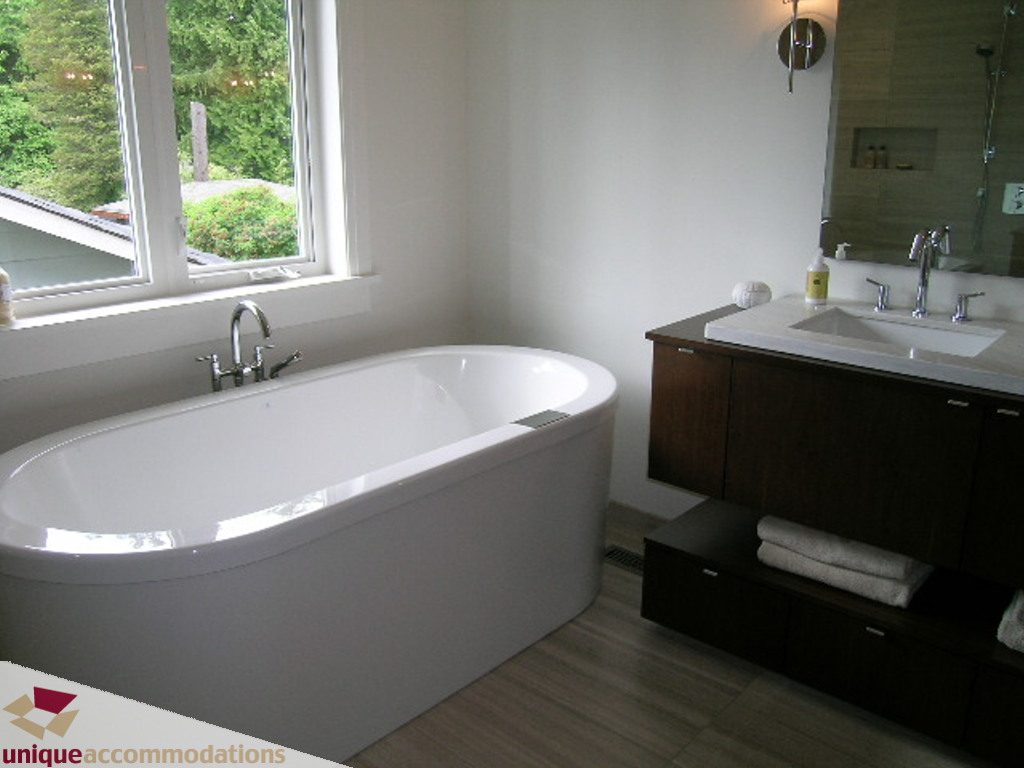 Spacious bathroom with a modern tub, dark wood cabinets, and a city view from the large window. - 2015 Lloyd Avenue, North Vancouver