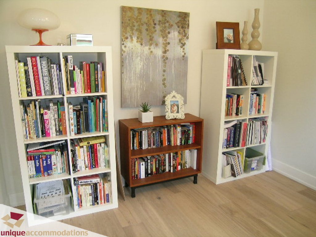 Spacious living room with white bookshelves, hardwood floors, and a modern abstract painting. - 2015 Lloyd Avenue, North Vancouver